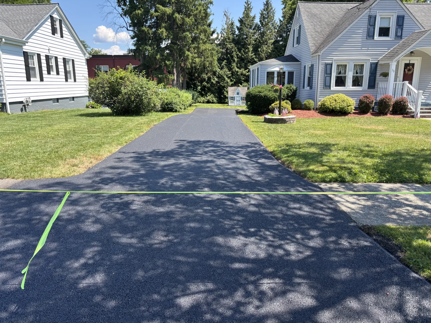 driveway-h A freshly paved asphalt driveway between two houses.